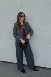 a lady in a red top, a sequin tweed jacket and a pair of grey pants